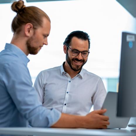 zwei Mitarbeiter sehen auf ein Notebook