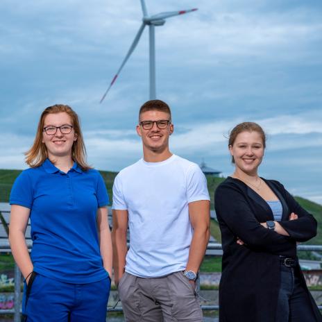 Bild mit drei Studierenden vor einem Windrad