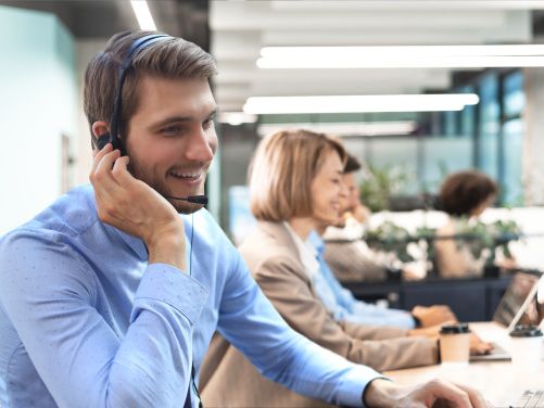 Mann in einem blauen Hemd mit einem Mikrofon bei einer Telefonberatung