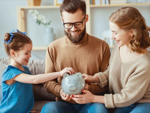 Fröhliche Familie mit einem Sparschwein in der Hand
