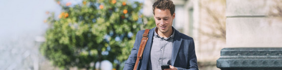 Mann läuft in der Stadt und schaut auf sein Handy