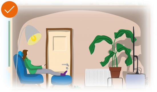 Frau sitzt mit dicken Socken auf einem Sessel im Wohnzimmer