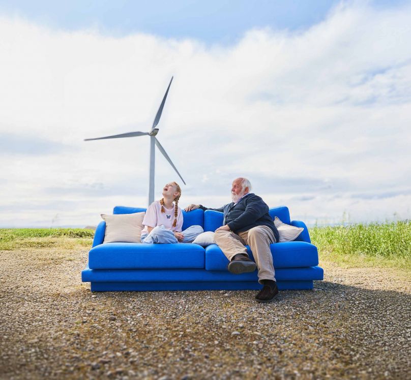Großvater und Enkelin sitzen auf einem blauen Sofa in freier Natur