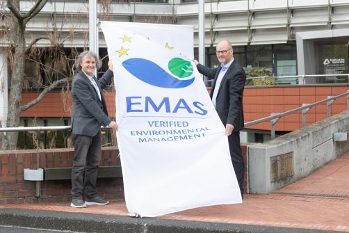 Hissen zum Jubiläum gemeinsam die EMAS-Flagge vor dem Gebäude der Stadtwerke: Markus Schleyer (links), der Leiter des Umweltbereiches und Dr. Olaf Heil, Technischer Geschäftsführer.