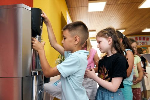 Kinder beim Auffüllen ihrer Becher am Trinkwassersprudler.