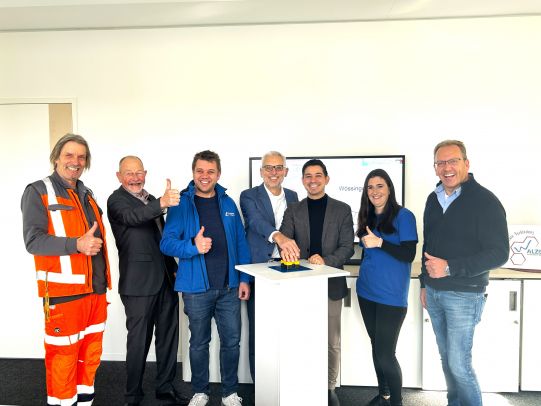 Zu sehen sind Matthias Maier (Mitte links), Bereichsleiter Trinkwasser bei den Stadtwerken, Bernd Hofmann (Zweiter von links), ehemaliger stv. Bereichsleiter Trinkwasser bei den Stadtwerken (im Ruhestand) und Timur Özcan (Mitte rechts), Bürgermeister der Gemeinde Walzbachtal sowie weitere an der Einführung des Prozessleitsystems Beteiligte. . Im Hintergrund auf dem Monitor ist das Leitsystem der Gemeinde Walzbachtal zu sehen. 