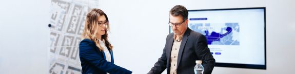 Zwei Personen stehend in einem Besprechungszimmer
